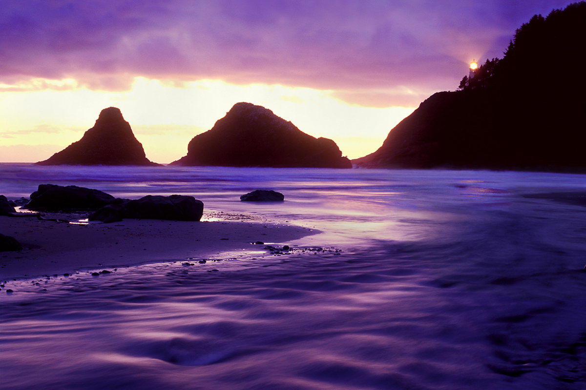 The guiding light of the Heceta Head lighthouse shines over a beautiful sunset.