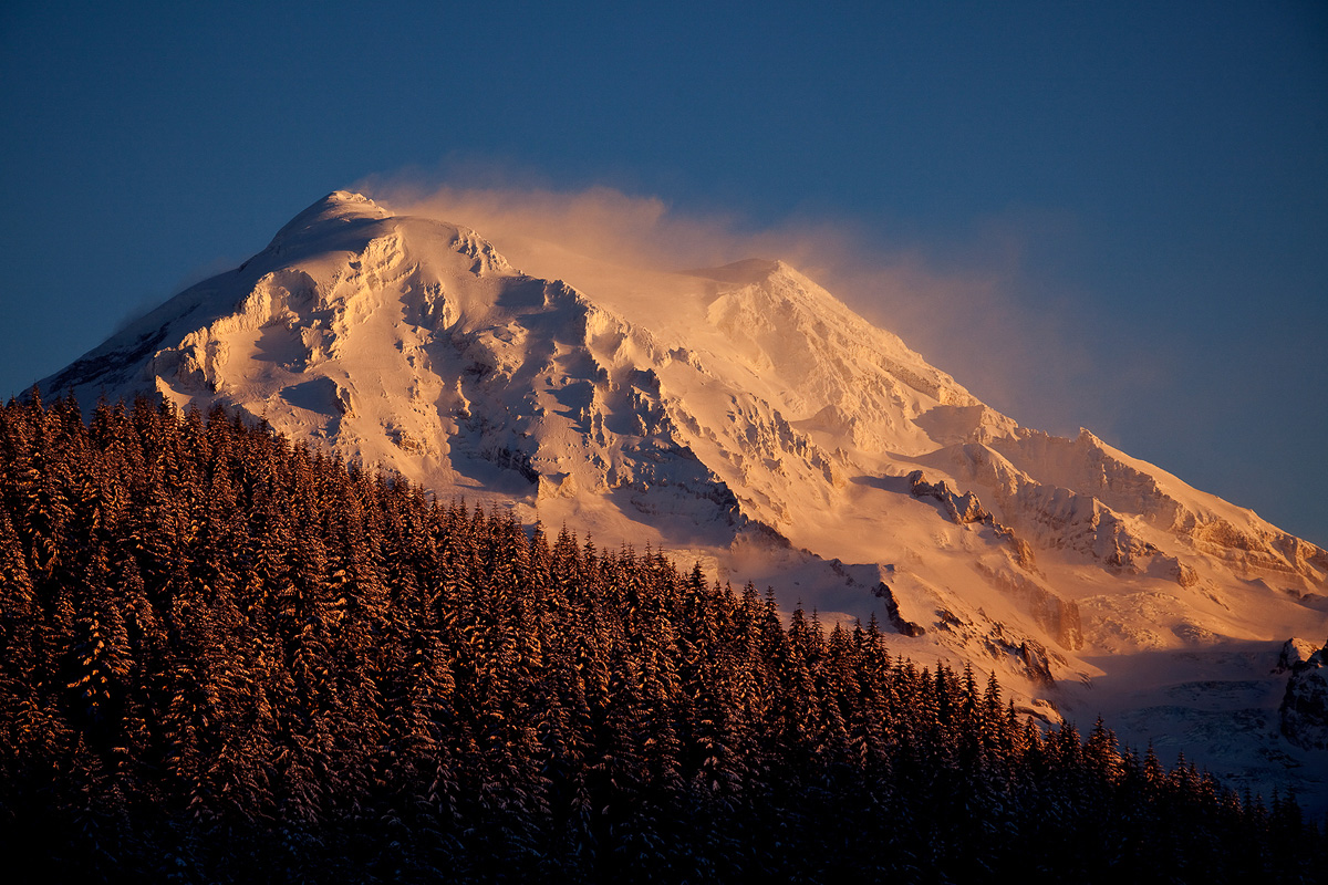 Raging wind blowing snow off the peak of Mt. Rainer in beautiful sunset light.