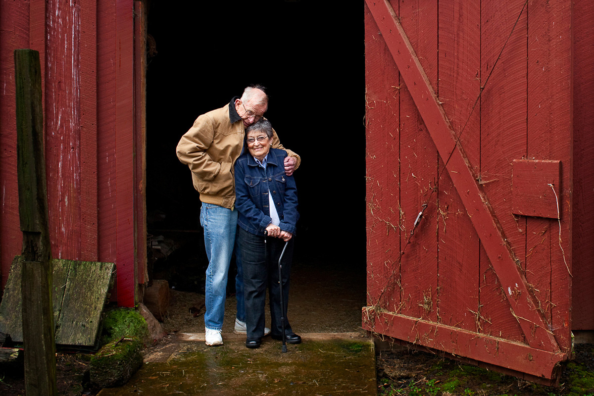 Older couple in doorway of old red barn