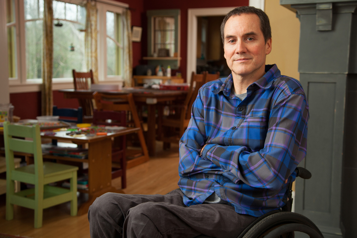 middle aged man sit in a wheelchair in his home