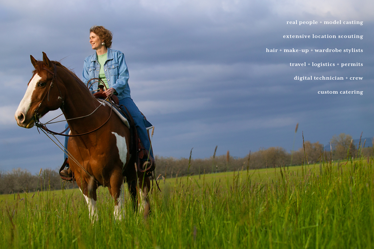 Middle aged woman on a horse in a green field with Spring clouds behind